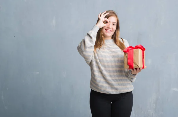 Mujer Adulta Joven Sobre Pared Grunge Gris Sosteniendo Regalo Con —  Fotos de Stock