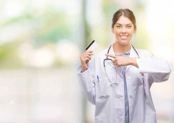 Jovem Hispânico Médico Mulher Segurando Cartão Crédito Muito Feliz Apontando — Fotografia de Stock