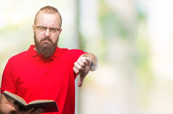 年轻的嬉皮士男子戴着眼镜 在孤立的背景上阅读一本书 带着愤怒的面孔 显示出不喜欢大拇指的负面标志 拒绝的概念 — 图库照片