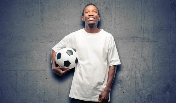 African black man holding soccer ball thinking and looking up expressing doubt and wonder