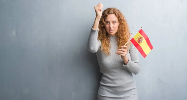 Joven Pelirroja Sobre Pared Grunge Gris Sosteniendo Bandera España Molesta —  Fotos de Stock