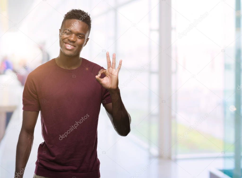 Young african american man doing ok sign with fingers, excellent symbol