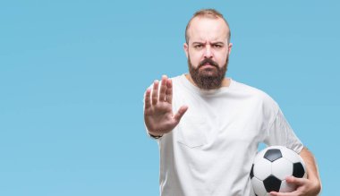 Açık eliyle dur işareti ile ciddi ve kendine güvenen ifade, savunma jest yapıyor izole arka plan üzerinde futbol futbol topu tutan genç beyaz hipster adam