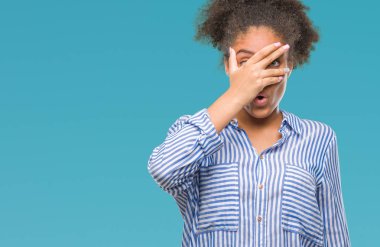 Yüz ve gözler el ile kapsayan şok bakmak izole arka plan üzerinde genç afro Amerikalı kadın mahcup ifadeyle parmaklarımın arasından arıyorsunuz.