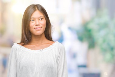 Genç Asyalı kadın görünümlü yan ve dik dik bakma uzağa düşünce gülümseyen izole arka plan üzerinde.