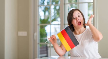 Down sendromu kadın evde bayrak gülümseyin ile çığlık zaferini kutluyor Almanya çok mutlu ve heyecanlı, kazanan ifade tutarak ve ellerini kaldırdı