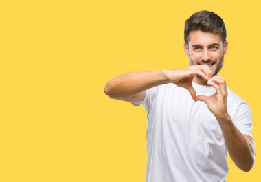 Yakışıklı delikanlı aşık kalp simgesi ve elleriyle şekil gösteren gülümseyen izole arka plan üzerinde. Romantik kavramı.