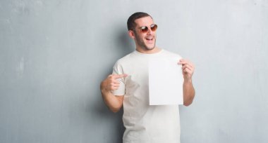 Boş kağıt çok mutlu el ve parmak ile işaret tutan gri grunge duvarın üzerinden beyaz delikanlı