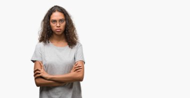 Yüz çapraz kolları üzerinde gözlük şüpheci ve sinir, onaylamayan ifade giyen güzel genç İspanyol kadın. Negatif kişi.