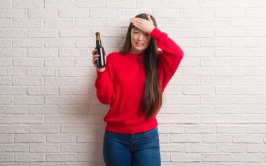 Baş, el ile vurguladı bira içme tuğla duvarın üzerinden Genç Çinli kadın şok utanç ve sürpriz suratla, öfkeli ve sinirli. Korku ve hata için üzgün.