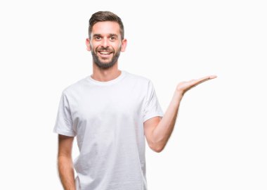 Genç yakışıklı adam neşeli sunulması ve kameraya bakarak avucunun ile işaret gülümseyen izole arka plan üzerinde.