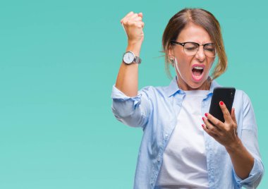 Orta yaş kadın kıdemli manifatura öfke, çılgın ve yükseltilmiş el, öfke kavramı ile diye bağıran ile smartphone üzerinde izole arka rahatsız ve sinirli bağırarak kullanarak ileti gönderme