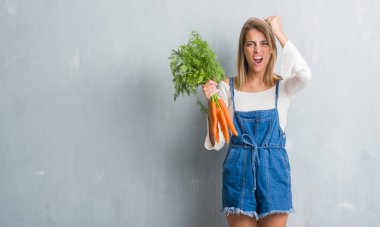 Grunge gri güzel genç kadın duvar taze havuç rahatsız tutarak ve boşa çıkarmak ile öfke, çılgın ve yükseltilmiş eliyle diye bağıran öfke kavramı bağırarak.
