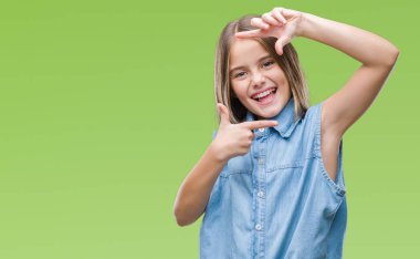 Genç güzel kız elle yapma çerçeve ve parmakları ile mutlu yüz gülümseyen izole arka plan yüzünden. Yaratıcılık ve Fotoğrafçılık kavramı.