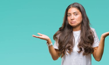 Genç güzel Arap kadın izole arka plan clueless ve şaşkın bir ifadeyle kollar ve eller kaldırdı. Şüphe kavramı.