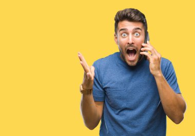 Smartphone üzerinde kocaman bir gülümseme ile çığlık zaferini kutluyor ve ellerini kaldırdı izole arka plan çok mutlu ve heyecanlı, kazanan ifade üzerinde konuşan genç yakışıklı adam