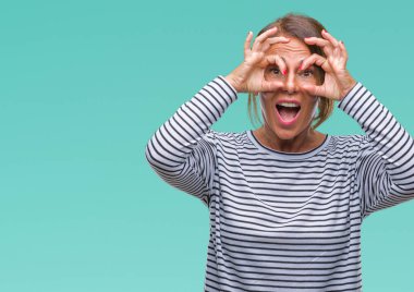 Orta yaş üst düzey İspanyol kadın dilini, parmaklarının arasından baktığını yapışmasını dürbün gibi ok jest yapıyor izole arka plan yüzünden. Deli ifade.