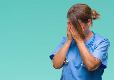 Orta yaş kıdemli hemşire doktor kadın ağlayarak süre elleriyle yüzünü kapsayan üzgün ifade ile izole arka plan yüzünden. Depresyon kavramı.