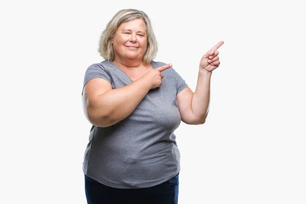 シニア プラス サイズ以上の白人女性分離笑顔で側に つの手と指で指しているカメラ目線の背景 — ストック写真