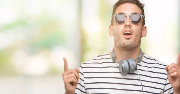 Joven Guapo Con Auriculares Asombrado Sorprendido Mirando Hacia Arriba Señalando —  Fotos de Stock