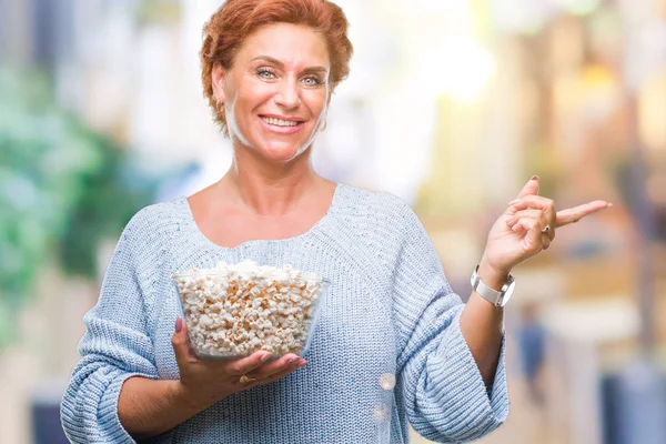 Attraktive Ältere Kaukasische Rothaarige Die Popcorn Über Isoliertem Hintergrund Isst — Stockfoto