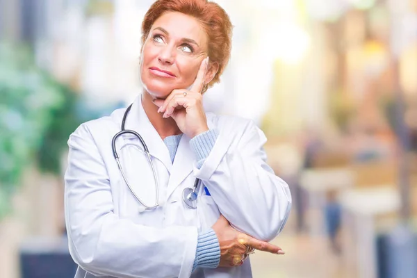 高级白种人医生妇女穿着医疗制服在孤立的背景与手下巴思考问题 沉思的表达 带着体贴的脸微笑 怀疑概念 — 图库照片