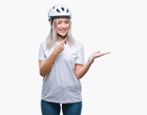 年轻的金发女子穿着自行车安全头盔在孤立的背景下 用手和手指指着脸 惊讶和微笑的相机 — 图库照片