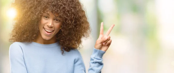 African American Kobieta Swetrze Uśmiecha Się Szczęśliwy Twarz Mrugając Aparat — Zdjęcie stockowe