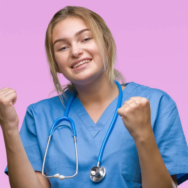 若い白人医師女性非常に幸せと興奮の腕を上げ 勝者のジェスチャを行う分離の背景の上の外科医の制服を着て笑顔で成功のために叫んで お祝いのコンセプト — ストック写真