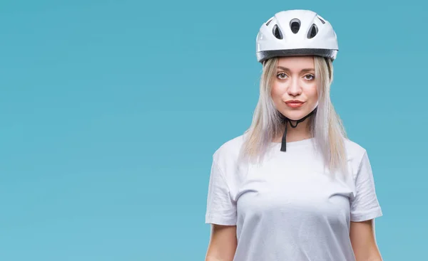 顔に真剣な表情で孤立した背景にサイクリスト セキュリティ ヘルメット身に着けている若いブロンドの女性 シンプルで自然なカメラを見てください — ストック写真