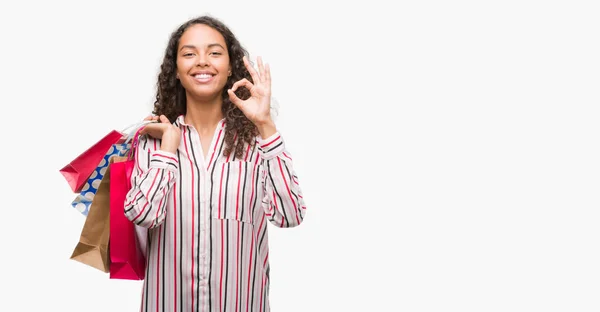 Unga Spansktalande Kvinna Som Håller Påsar Gör Tecken Med Fingrarna — Stockfoto