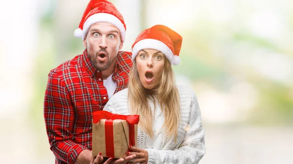 Pareja Joven Enamorada Vistiendo Sombrero Navidad Sosteniendo Presente Sobre Fondo — Foto de Stock