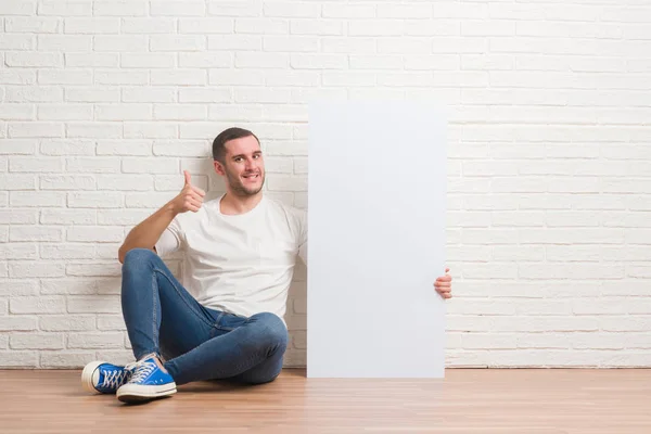 Junger Kaukasischer Mann Sitzt Über Weißer Ziegelwand Und Hält Eine — Stockfoto