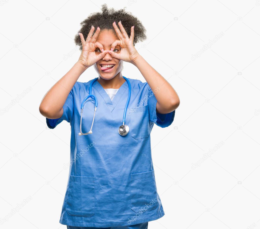 Young afro american doctor woman over isolated background doing ok gesture like binoculars sticking tongue out, eyes looking through fingers. Crazy expression.