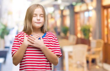 Genç güzel kız ile gülümseyen izole arka plan üzerinde kapalı gözler ve yüzünde minnettar jest ile göğüs üzerinde eller. Sağlık kavramı.