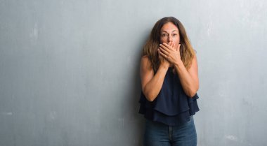 Gri grunge duvar eller için hata ile ağız kapsayan şok üzerinde duran orta yaş İspanyol kadın. Gizli kavramı.