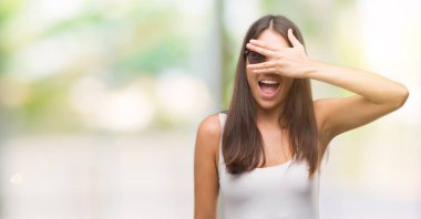 Mahcup ifadeyle parmaklarımın arasından seyir yüz ve gözler el ile kapsayan şok bakmak güneş gözlüğü takmış genç güzel İspanyol.