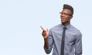 Kameraya bakarak yan el ve parmak ile işaret eden genç Afro-Amerikalı iş adamı yüzünde kocaman bir gülümseme ile izole arka plan üzerinde.