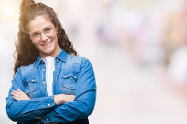 Güzel genç esmer kıvırcık saçlı kız üzerinde gözlük ile mutlu yüz gülümseyerek kameraya seyir silah geçti arka plan izole. Olumlu bir kişi.