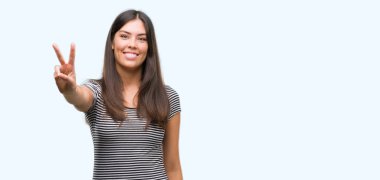 Zafer işareti yapıyor parmak gösterilen kamera seyir gülümseyen genç güzel İspanyol kadın. İki numaralı.