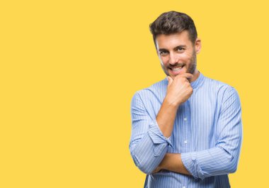 Yakışıklı delikanlı emin çapraz kollar ve çeneme kaldırdı el ile gülümseme ile kameraya bakarak izole arka plan üzerinde. Pozitif düşünce.