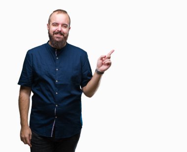 Kameraya bakarak yan el ve parmak ile işaret eden genç beyaz hipster adam yüzünde kocaman bir gülümseme ile izole arka plan üzerinde.