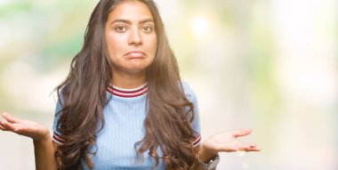 Genç güzel Arap kadın izole arka plan clueless ve şaşkın bir ifadeyle kollar ve eller kaldırdı. Şüphe kavramı.