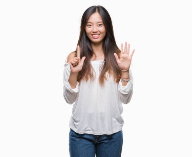 Genç Asyalı kadın gösterilen ve parmakları ile işaret izole arka plan üzerinde kendinden emin ve mutlu gülümseyerek süre yedi numara.