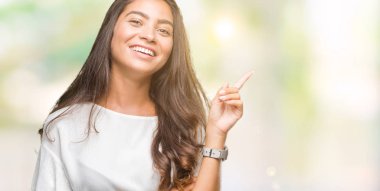 Yüzünde kocaman bir gülümseme ile izole arka plan üzerinde genç güzel Arap kadın kameraya bakarak yan el ve parmak ile işaret.