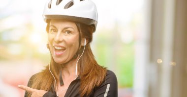 Orta yaş bisikletçi kadın uzak yan parmak ile işaret kulaklık kullanarak