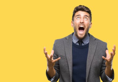 Genç yakışıklı iş adamı izole arka plan çılgın ve kızgın bağırarak ve agresif ifade ve silah kaldırdı bağırıyor. Hayal kırıklığı kavramı.