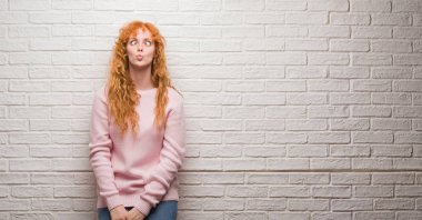 Tuğla duvar yapım balık yüzüne dudaklı, çılgın ve komik bir jest duran genç Kızıl saçlı kadın. Komik ifade.