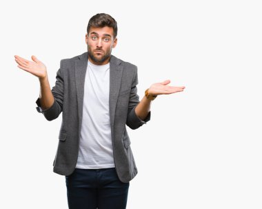 Genç yakışıklı iş adamı izole arka plan clueless ve şaşkın bir ifadeyle kollar ve eller ortaya çıkar üzerinden. Şüphe kavramı.