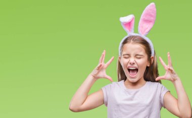 Young beautiful girl wearing easter bunny ears over isolated background celebrating mad and crazy for success with arms raised and closed eyes screaming excited. Winner concept clipart